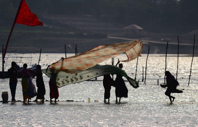 Image: Indian women dry their saris after taking a dip at Sangam