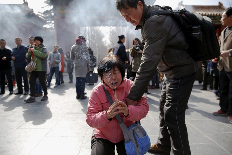 Image: A crying woman falls on her knees as relatives of passengers onboard of Malaysia Airlines flight MH370 which went missing in 2014, burn incense sticks and pray at Lama Temple in Beijing