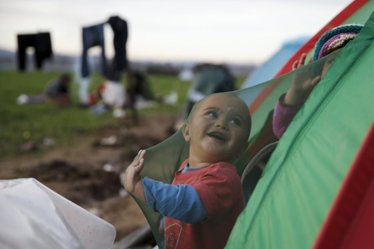 Image: A migrant who is waiting to cross the Greek-Macedonian border, plays in his tent at a makeshift camp near the village of Idomeni, Greece
