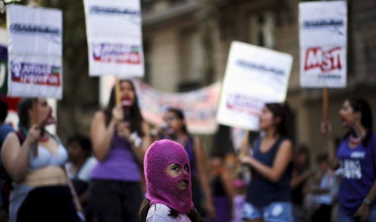 Image: A girl wears a mask as women shout slogans during a demonstration to mark International Women's Day and to demand policies to prevent femicides outside the Congress in Buenos Aires
