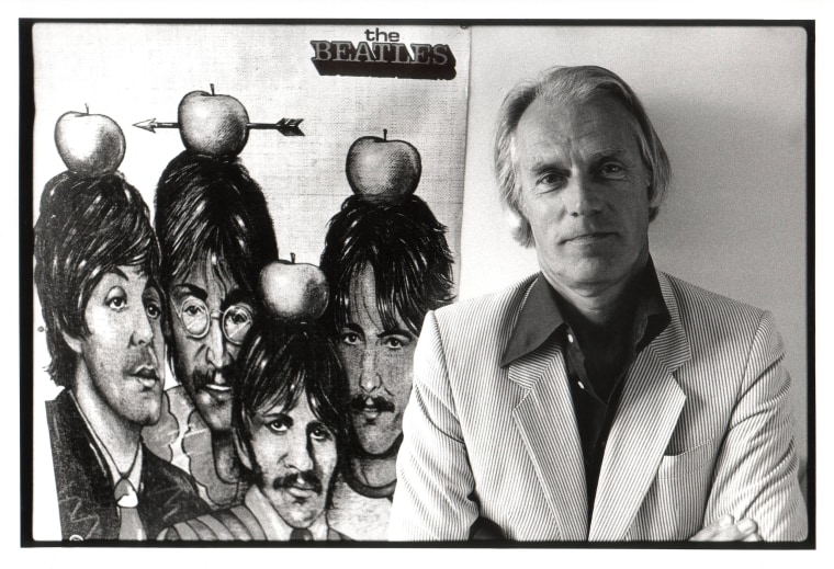 Image: George Martin poses next to a poster of the Beatles