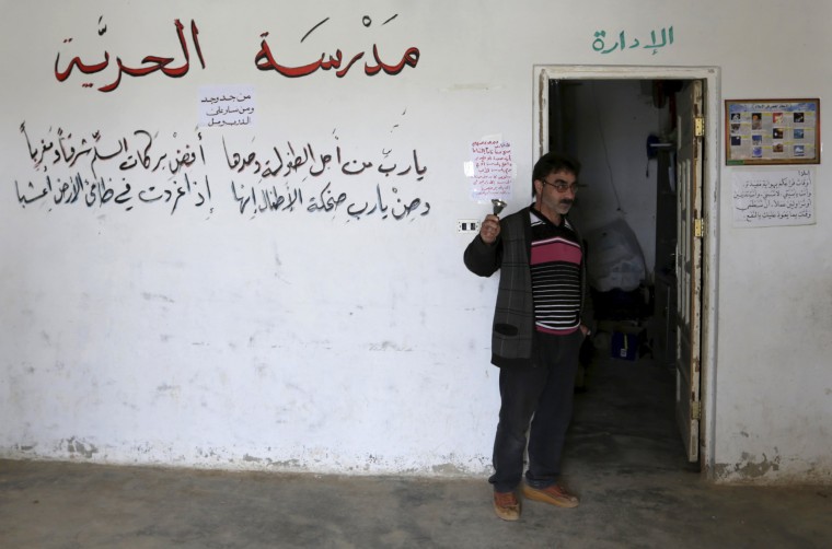 Image: A teacher rings a bell inside the Freedom School, in the town of al-Tamanah, in the southern countryside of Idlib