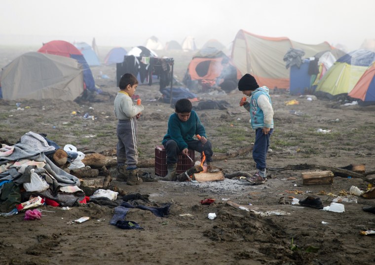 Image: Children eat by a fire at the northern Greek border station of Idomeni, Friday.