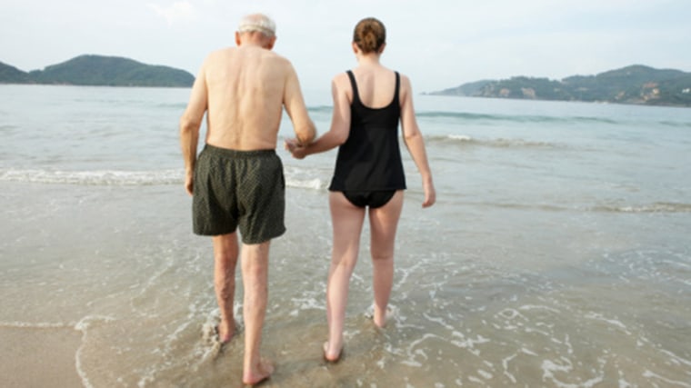 Image: Older man and young woman walking in the ocean.