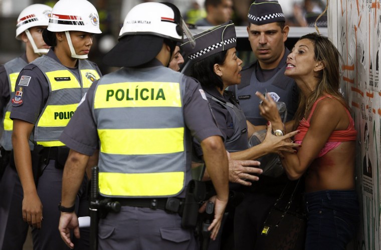 Image: A demonstrator argues with policewomen after she turned up her shirt