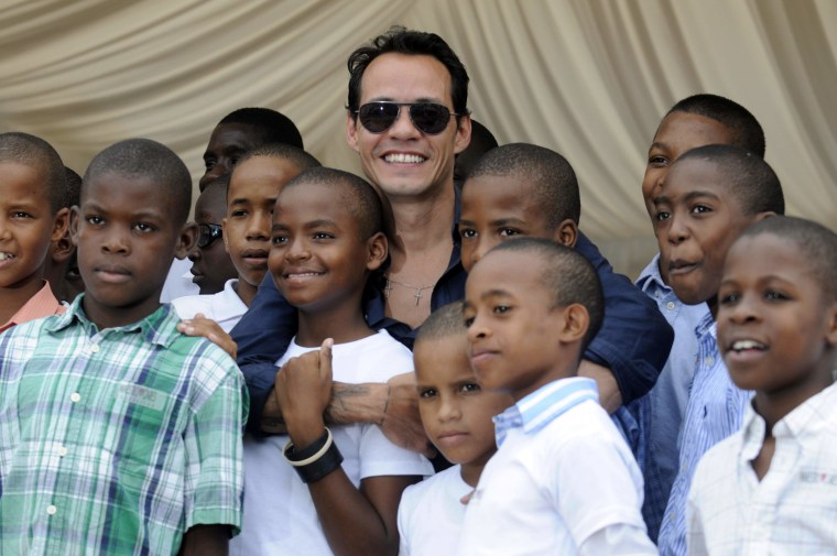 Image: Marc Anthony smiles with children from Children of Christ Orphanage during a ceremony to mark the start of the expansion of the orphanage in La Romana