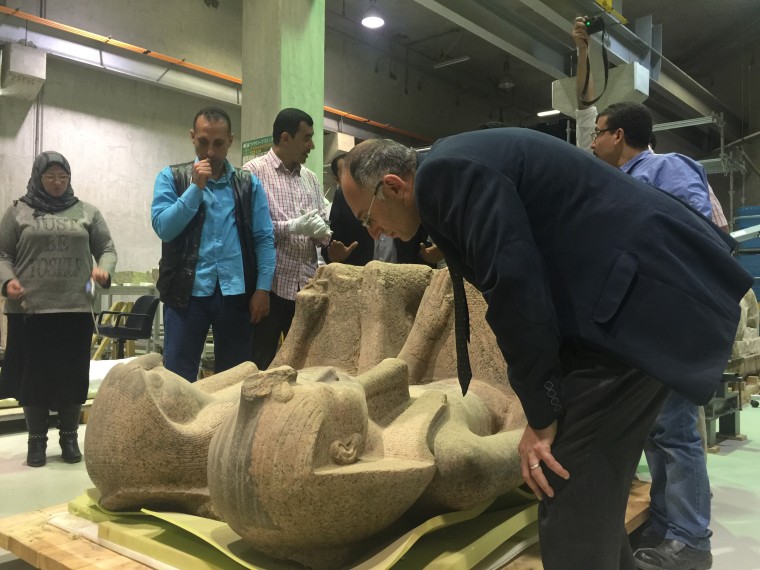 Image: Tarek Tawfiq examines the 3,500-year-old statue
