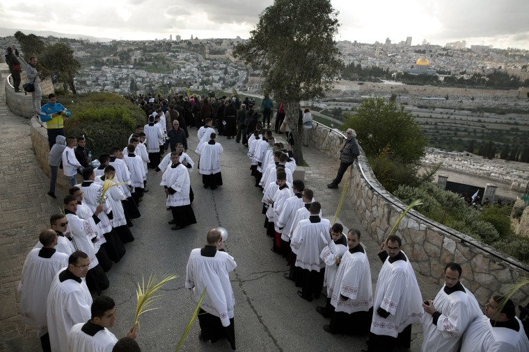 Image: Christian priests, some holding palm fronds participate in the traditional Palm Sunday procession