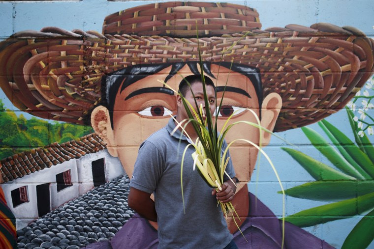 Image: A man holds palm fronds during a Palm Sunday celebration in Nahuizalco
