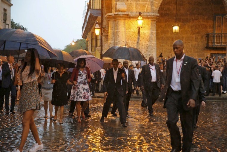 Image: President Obama steps over a puddle while touring Old Havana with his family