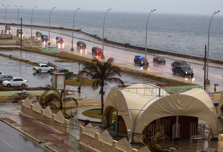 Image: The convoy carrying President Barack Obama and his family drives in the rain along the Malecon sea wall, past an artisan market in Havana