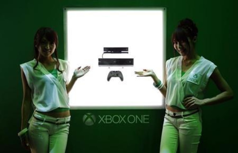 Booth girls stand next to Microsoft's new game console Xbox One at the Tokyo Game Show in Chiba