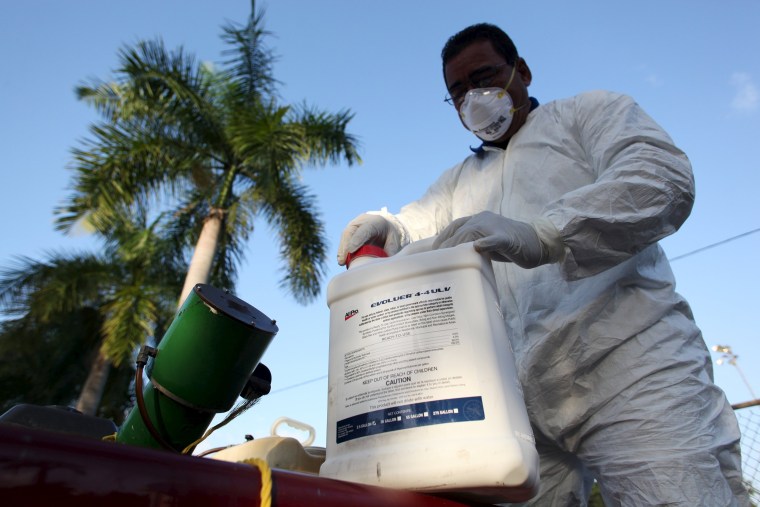 Image: A health worker prepares insecticide before fumigating in a neighborhood in San Juan.