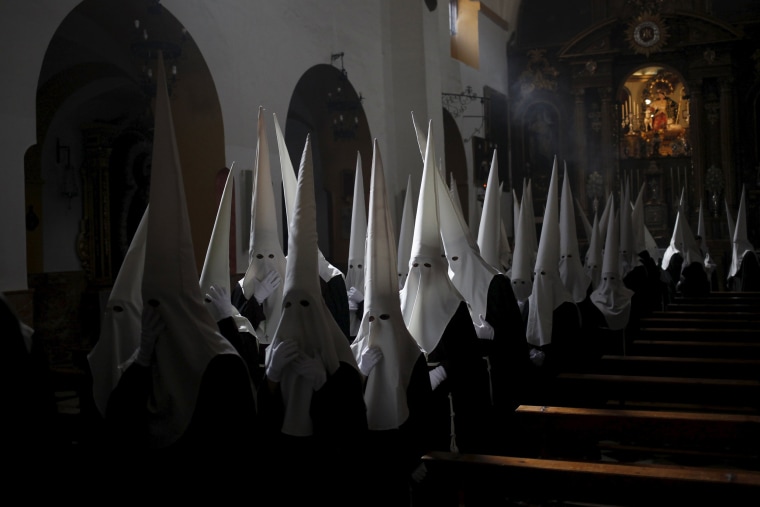 Image: Penitents of \"Dulce Nombre\" brotherhood wait inside a church before they take part in a procession during Holy Week in Malaga