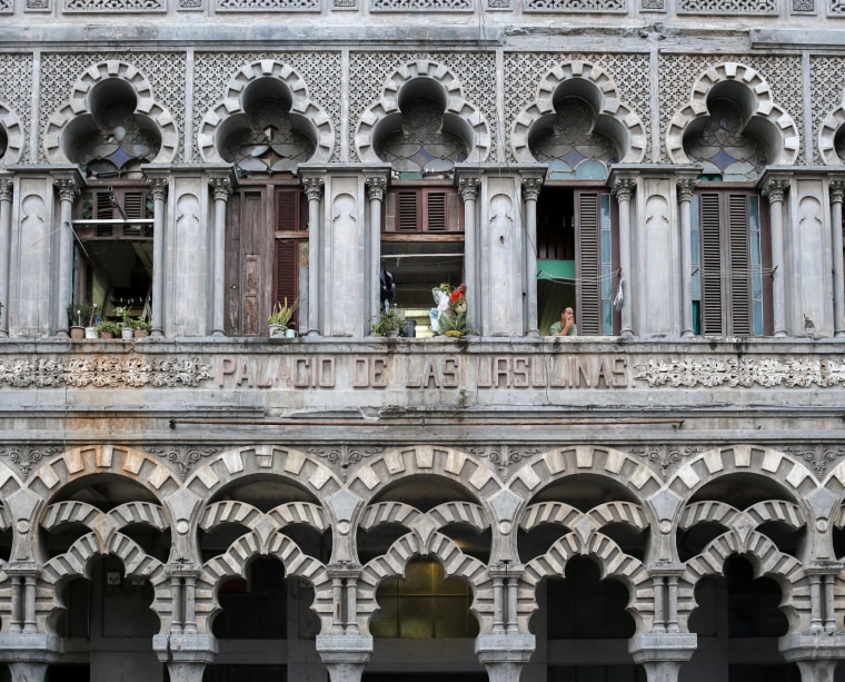 A man looks out the window in Havana.