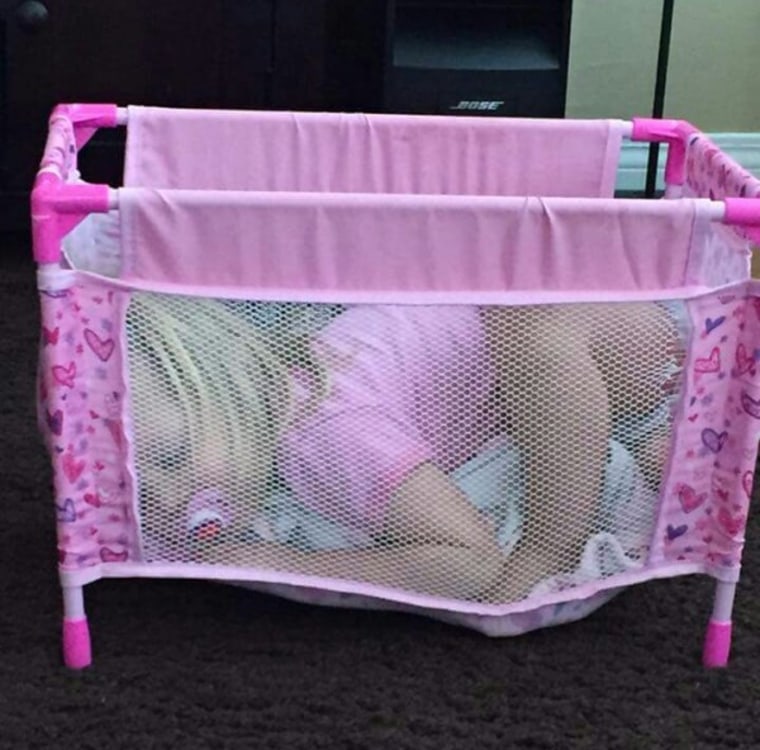 Girl sleeping in tiny playpen