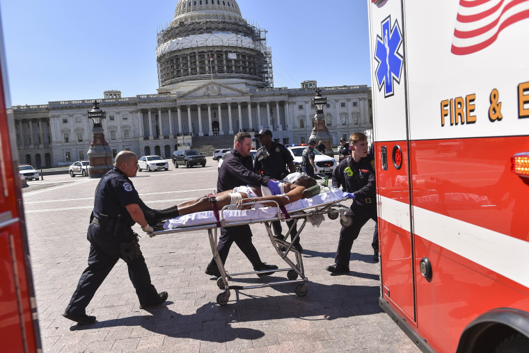 Image: Police and EMS personnel transport the person believed to be the gunman away from the shooting scene at the U.S. Capitol