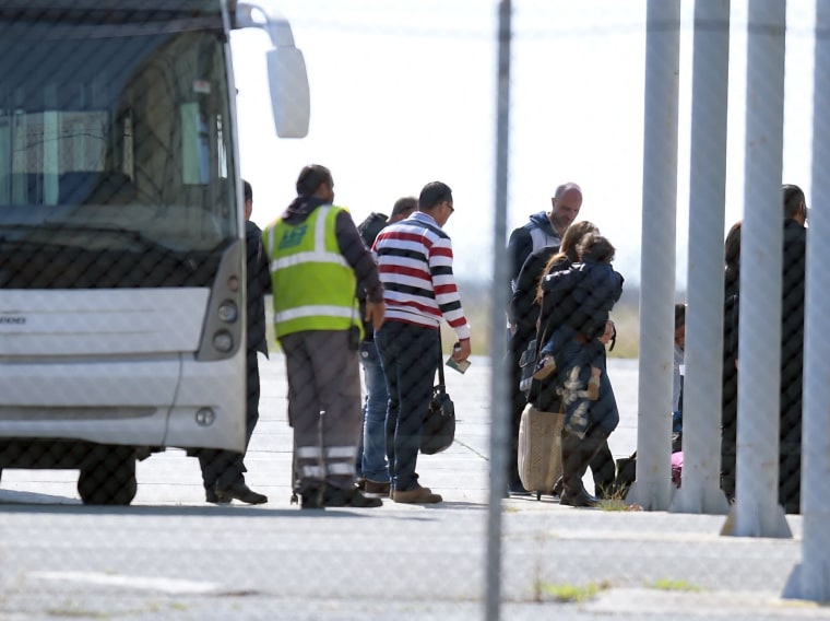 Image: Passengers leave the bus after disembarking the plane