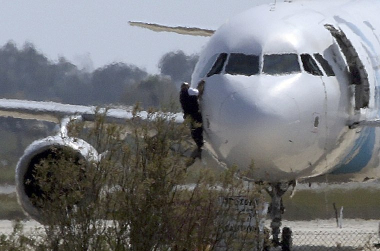 Image: A man climbs out of the cockpit window of the hijacked Egyptair Airbus A320 at Larnaca Airport in Larnaca, Cyprus