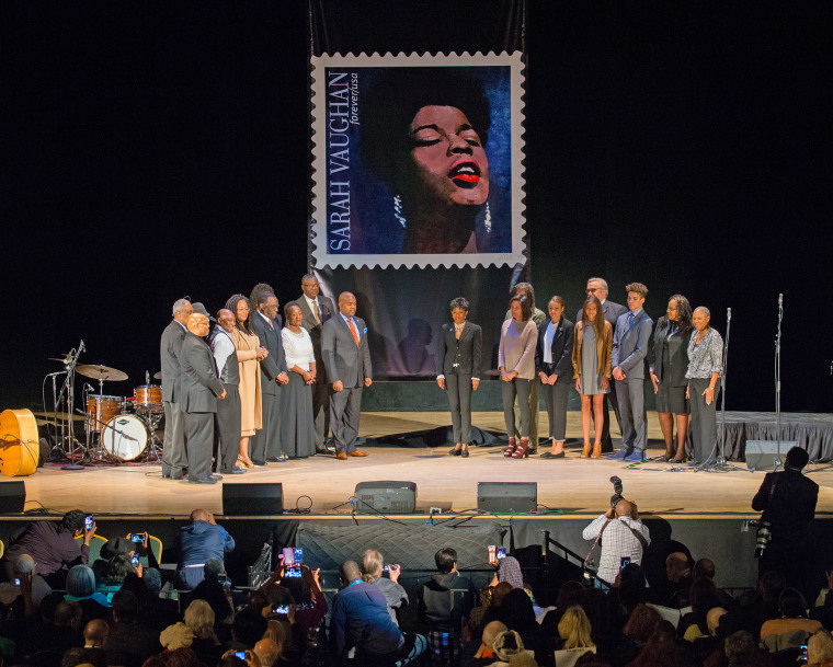 Participants gather on stage following stamp unveiling for late jazz singer Sarah Vaughan