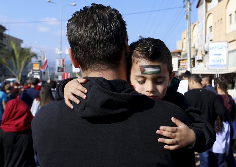 Image: An Israeli Arab boy sleeps as his father carries him during a Land Day rally in the northern Israeli village of Arrabe