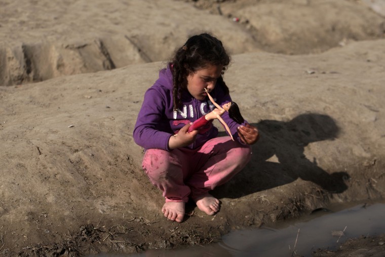 Image: A migrant girl plays with her doll at the makeshift camp at the Greek-Macedonian border