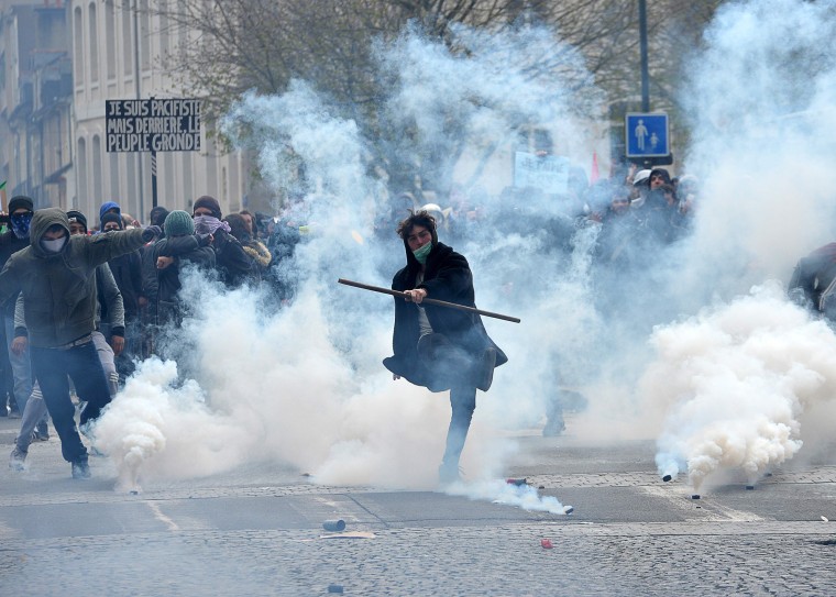 Image: A protester kicks back a tear gas canister at riot police during a demonstration against the French government's labor law reforms
