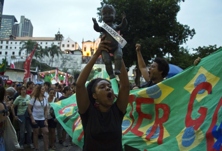 Image: A woman holds a doll in the air during a rally in Rio de Janeiro