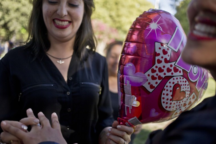 A woman slips a ring on the finger of her partner during a mock wedding as part of a Valentine's Day event.