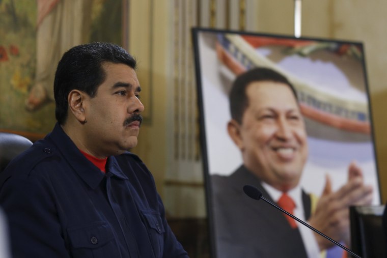 Image: Venezuela's President Nicolas Maduro speaks next to a picture of Venezuela's late President Hugo Chavez in Caracas