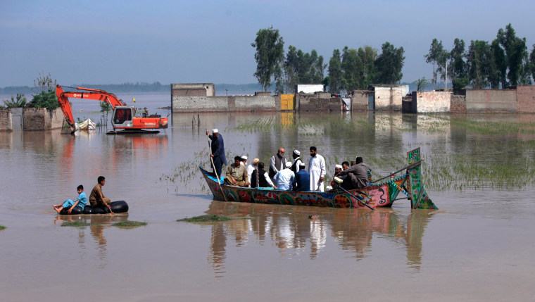 Image: Residents use boats and inner tubes to float around in floodwater after heavy rain on the outskirts of Peshawar