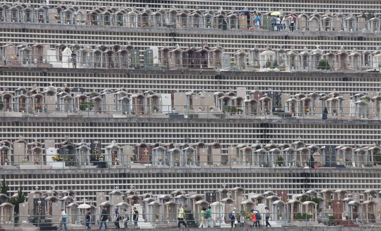 Image: People pay respect to the dead at Cape Collinson cemetery
