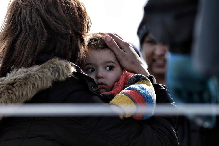 Image: A mother holds her child as migrants arrive on a Greek coast guard boat