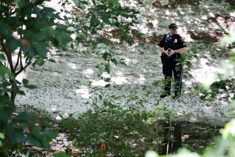 Image: An officer stands watch in the bed of Waller Creek on the University of Texas campus in Austin