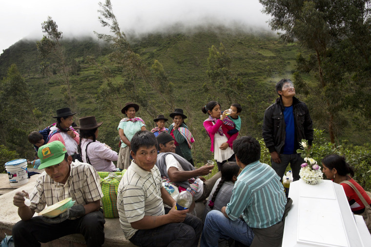 Image: People eat and visit during a burial for over 30 villagers killed more than two decades ago