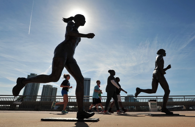 Image: Runners make their way past the River Runner statues