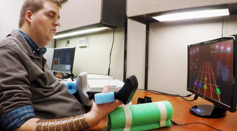Ian Burkhart, 24, plays a guitar video game as part of a study into neural bypass technology that allowed him to regain functional use of his paralyzed hand.