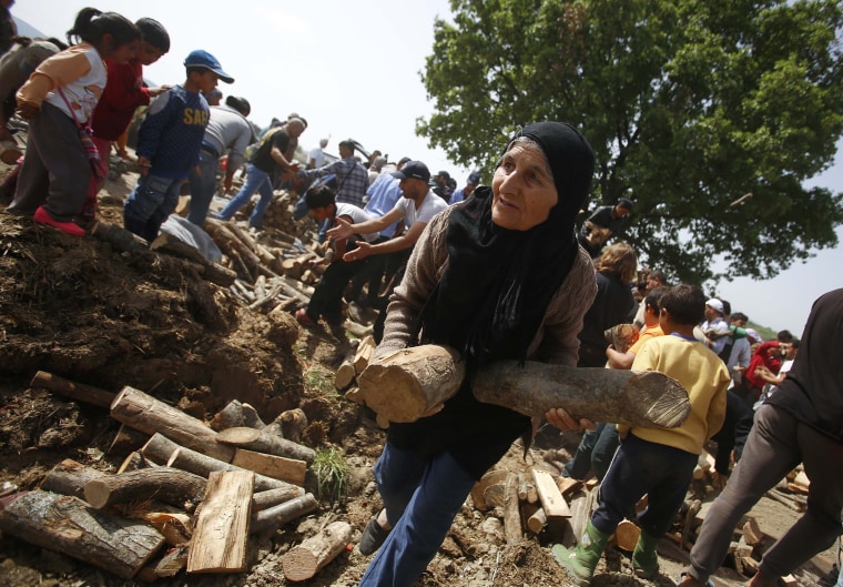 Image: A woman holds fire wood distributed near a makeshift migrant camp near Idomeni