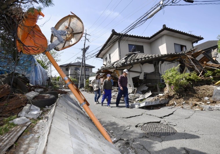 Image: Residents walk past a house damaged by a magnitude-6.5 earthquake in Mashiki, Kumamoto prefecture, southern Japan