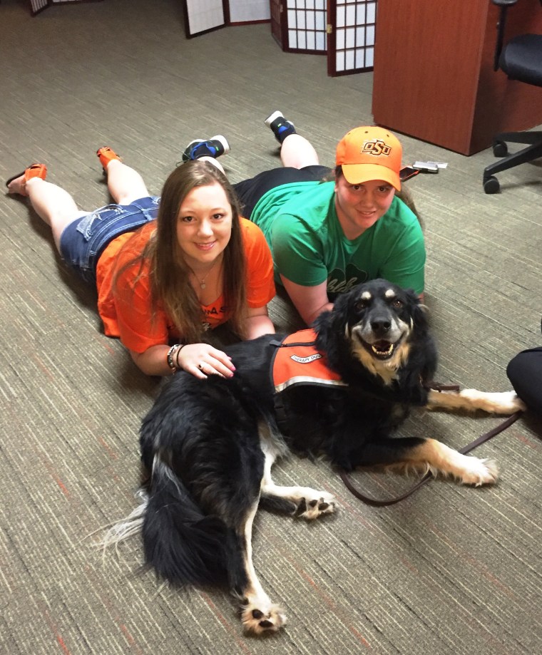 Students Amanda Slife and Ashley Waters relax with Evie the dog at the Oklahoma State University Reboot Center.