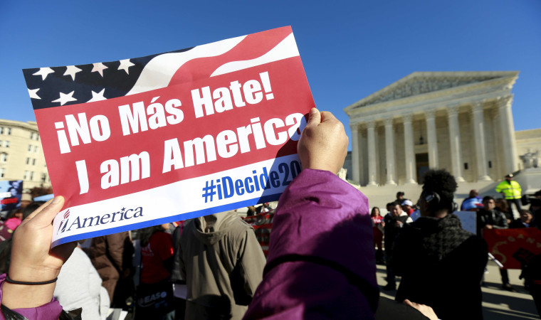 Image: A protester holds a sign as immigrants and community leaders rally in front of the U.S. Supreme Court in Washington