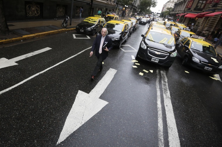 Image: A man walks through taxi drivers blocking an avenue to protest Uber in downtown Buenos Aires