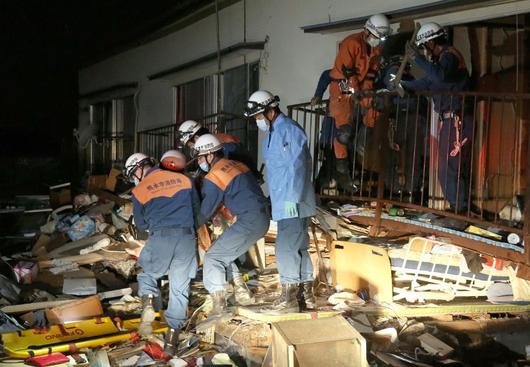 Image: Rescue workers save a person from a collapsed building in Kuammoto