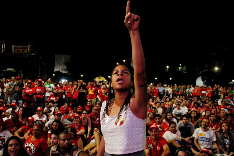 Image: A woman gestures to a big screen while following the proceedings