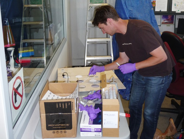 Image: Researcher John Chase samples office surface materials just prior to installation