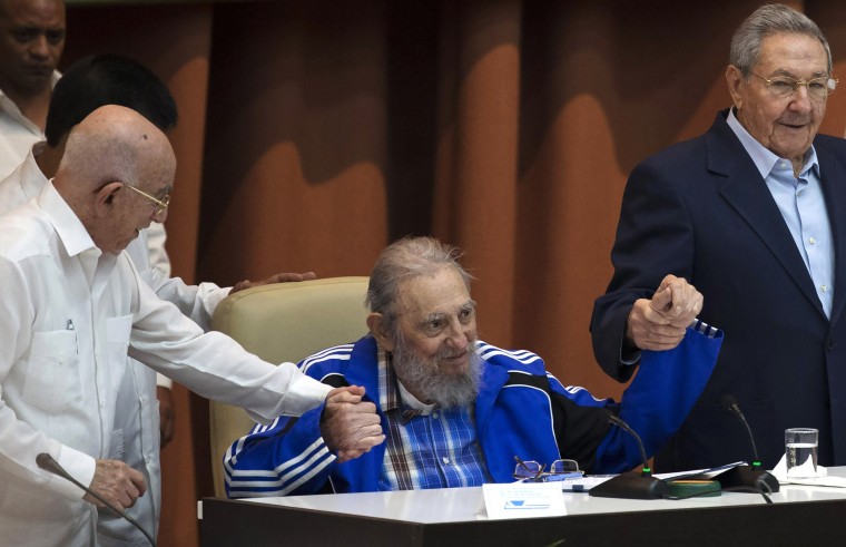 Image: Fidel Castro sits as he clasps hands with his brother