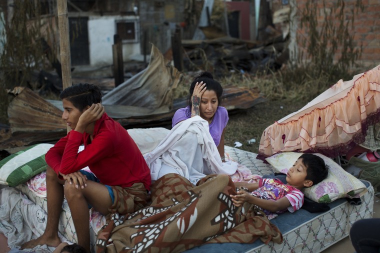 Image: A family wake up after sleeping outside their collapsed home in Manta, Ecuador