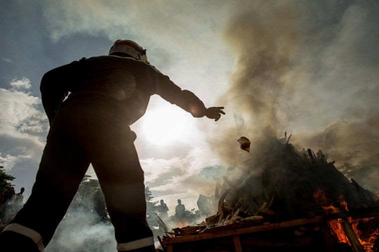 Image: A firefighter throws a plastic bag of accelerant onto the first ever Cameroon Ivory Burn