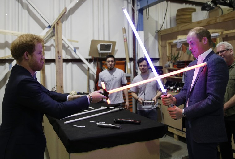 Image: Britain's Prince William, right, and Prince Harry use light sabers