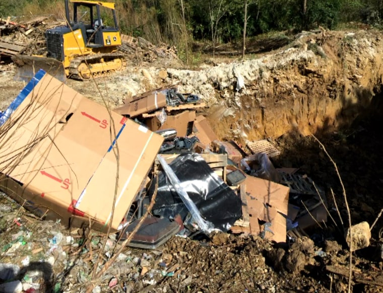 A bulldozer is parked next to a hole in the ground filled with televisions and other electronics in an illegal landfill in Scott County, Kentucky. Global Environmental Service confessed to the illegal dumping.